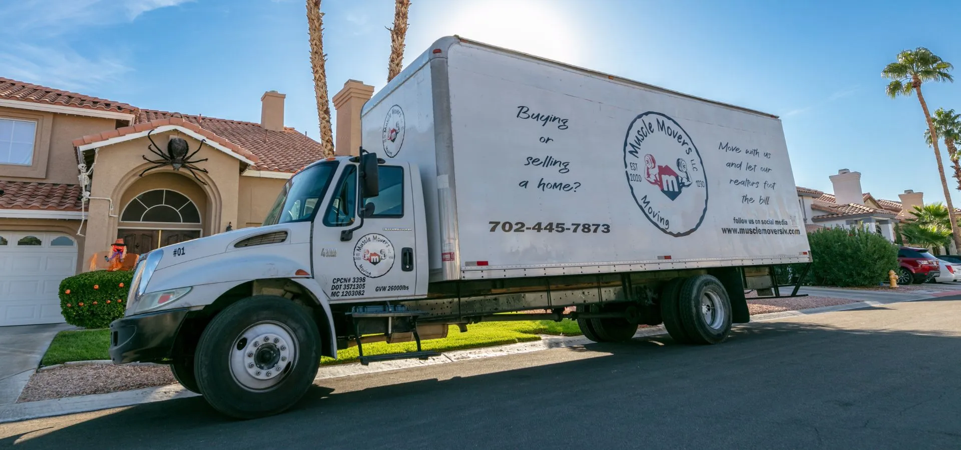 A branded Muscle Movers truck parked outside a Las Vegas home with the ramp down.
