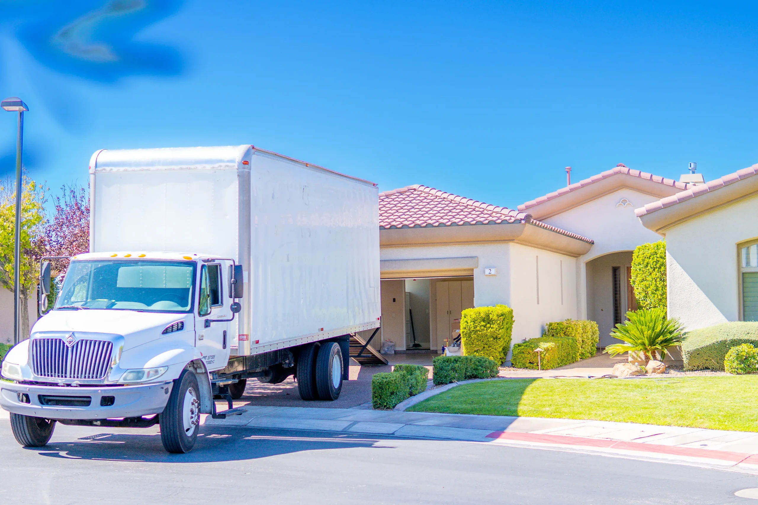 A Muscle Movers box truck parked outside a stucco home.